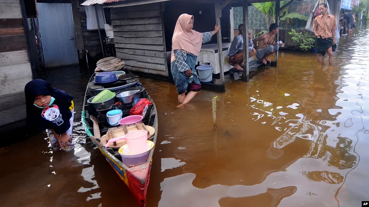 People talk outside their homes at a neighborhood affected by flood in Banjarmasin, South Kalimantan on Borneo Island, Indonesia, Jan. 17, 2021.