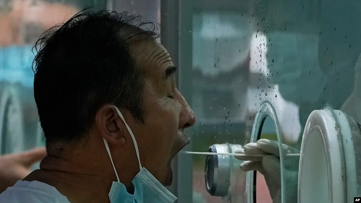 A man pulls his mask to get his routine COVID-19 throat swab at a coronavirus testing site in Beijing, Aug. 9, 2022.