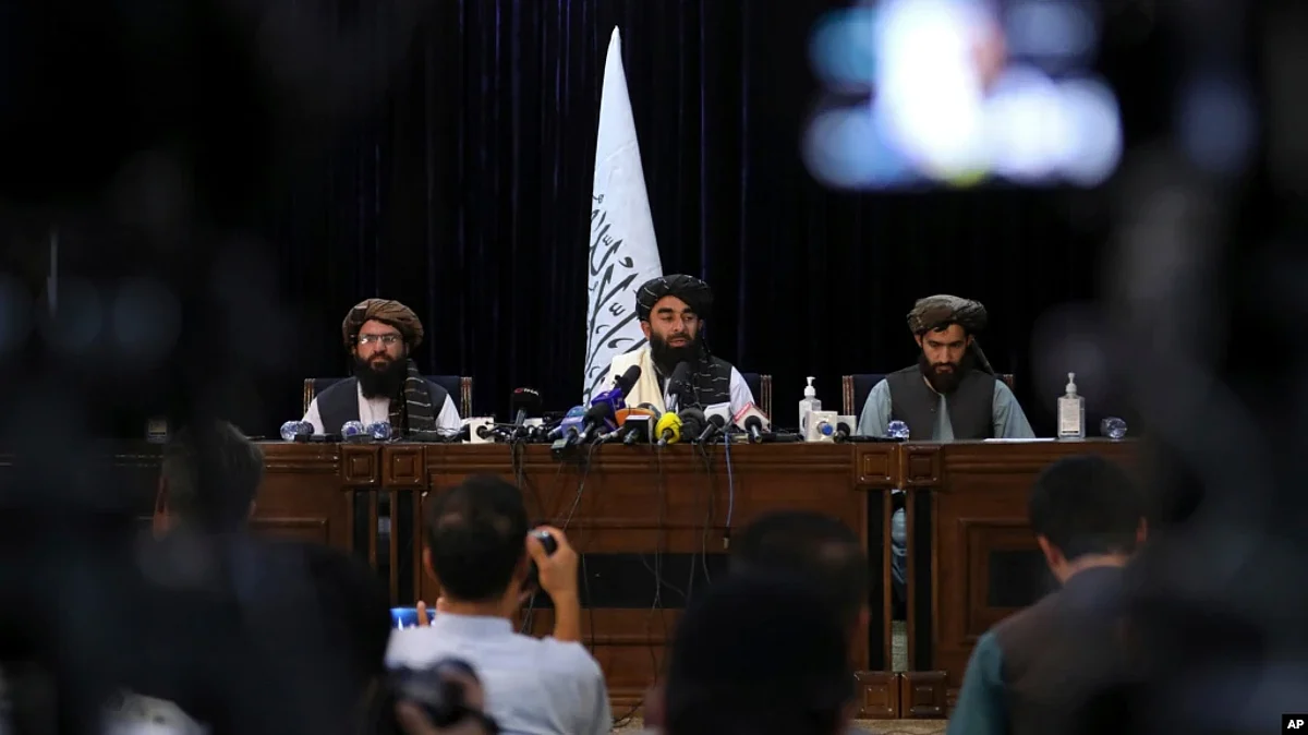 In front of a Taliban flag, then-Taliban spokesman Zabihullah Mujahid, centre, speaks at his first news conference, in Kabul, Afghanistan, Aug. 17, 2021.