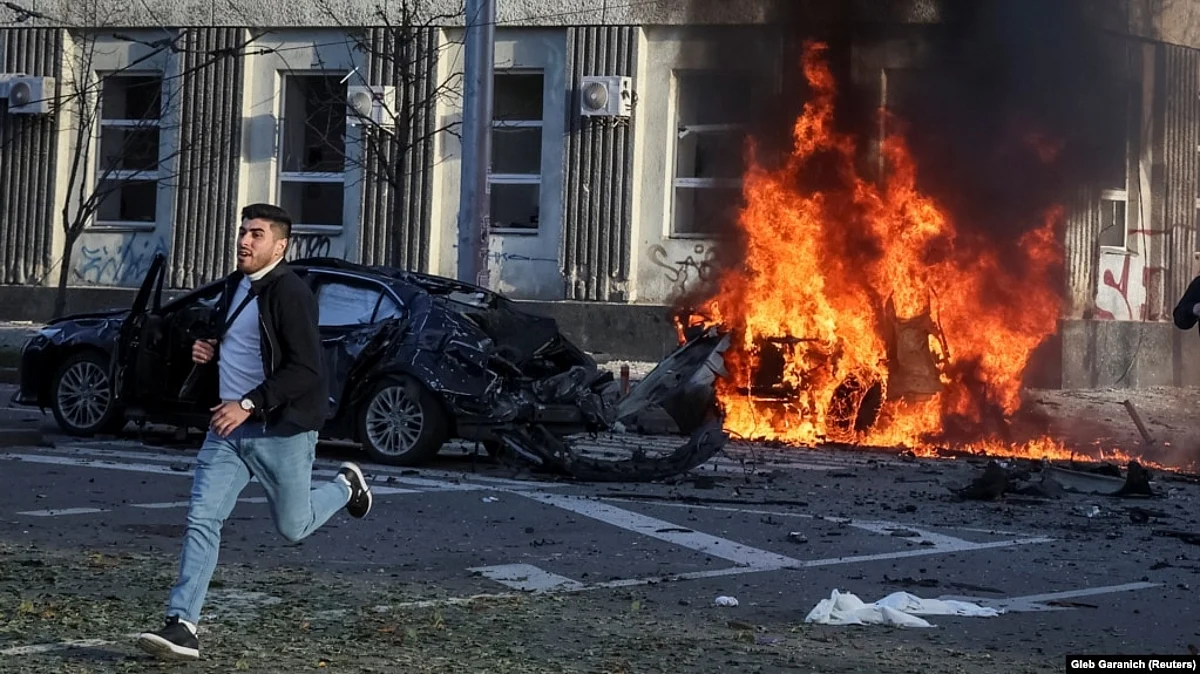 A man runs from the scene as a car burns on a Kyiv street following Russian military strikes on the Ukrainian capital on October 10.