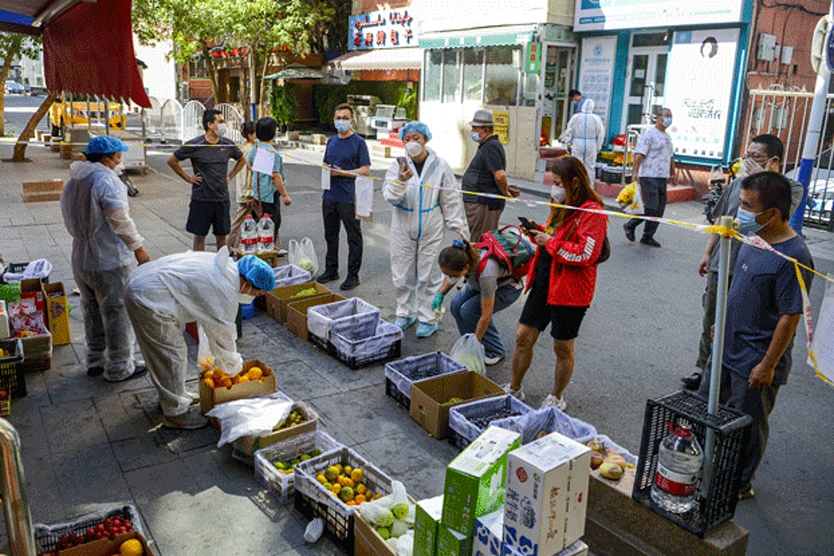 Residents standing behind a cordon line shop at a fruit stall amid a COVID-19 outbreak in the Tianshan district of Urumqi, capital of northwestern China's Xinjiang Uyghur Autonomous Region, Sept. 5, 2022.