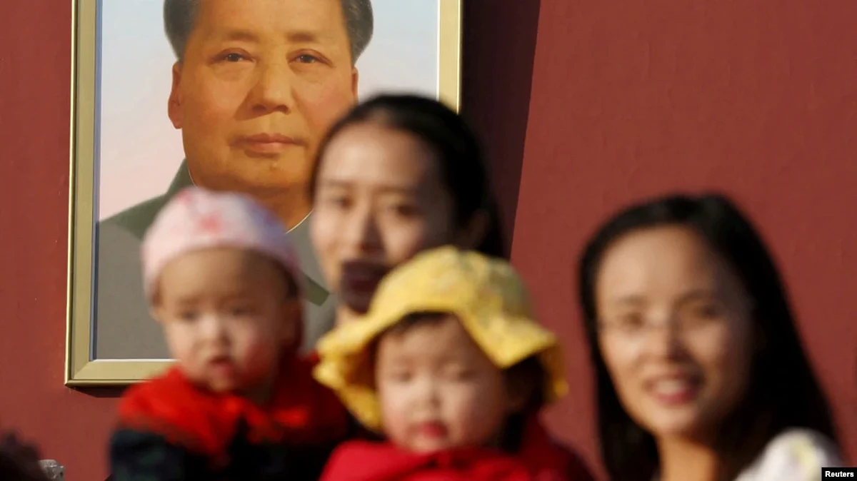 FILE - Two women and their babies pose for photographs in front of the giant portrait of late Chinese chairman Mao Zedong on the Tiananmen Gate in Beijing Nov. 2, 2015.