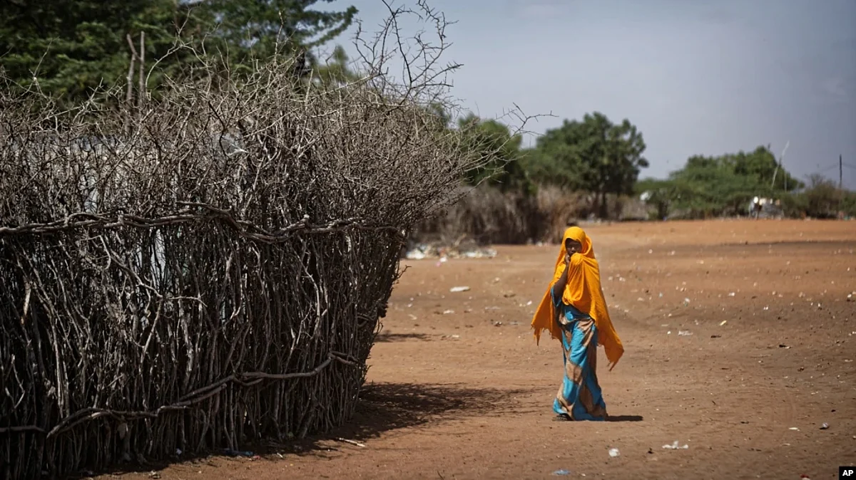 FILE - In this Dec. 19, 2017 photo, a Somali girl walks near a fence surrounding a hut at Dadaab refugee camp-AP