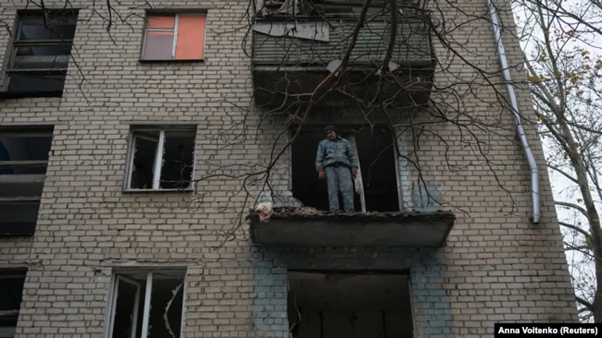 Man looks down on destruction from damaged apartment of residential building in Kherson. (Reuters)