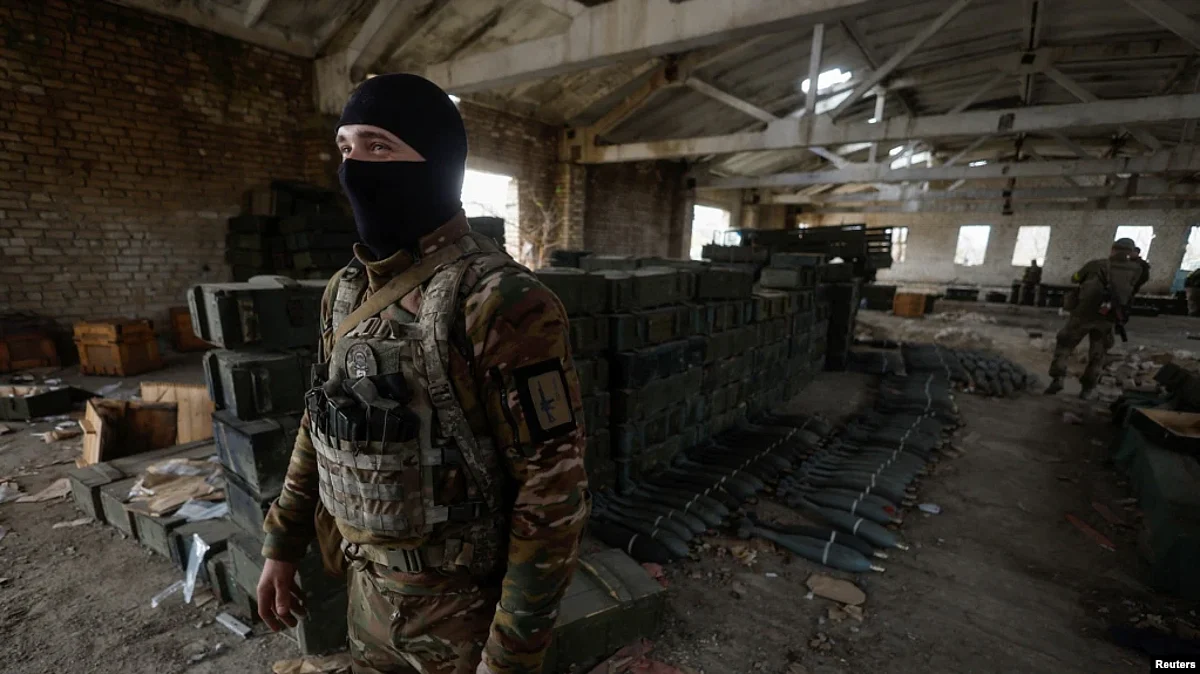 A Ukrainian soldier stands next to cases of ammunition abandoned by retreating Russian forces in the village of Blahodatne, in Ukraine's Kherson region, Nov. 11, 2022.