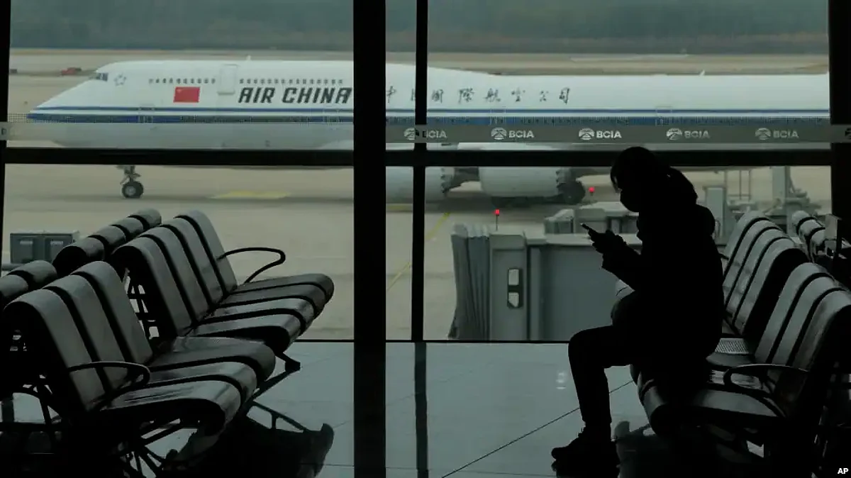 FILE - A passenger checks her phone as an Air China passenger jet taxis past at Beijing Capital International airport, in Beijing, Oct. 29, 2022. China will drop a COVID-19 quarantine requirement for passengers arriving from abroad starting Jan. 8, 2023. (AP)