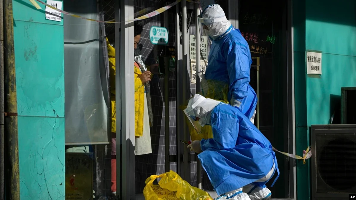 Workers in protective gear prepare to collect COVID samples from a woman at her locked-down store in Beijing, Dec. 1, 2022. (AP)