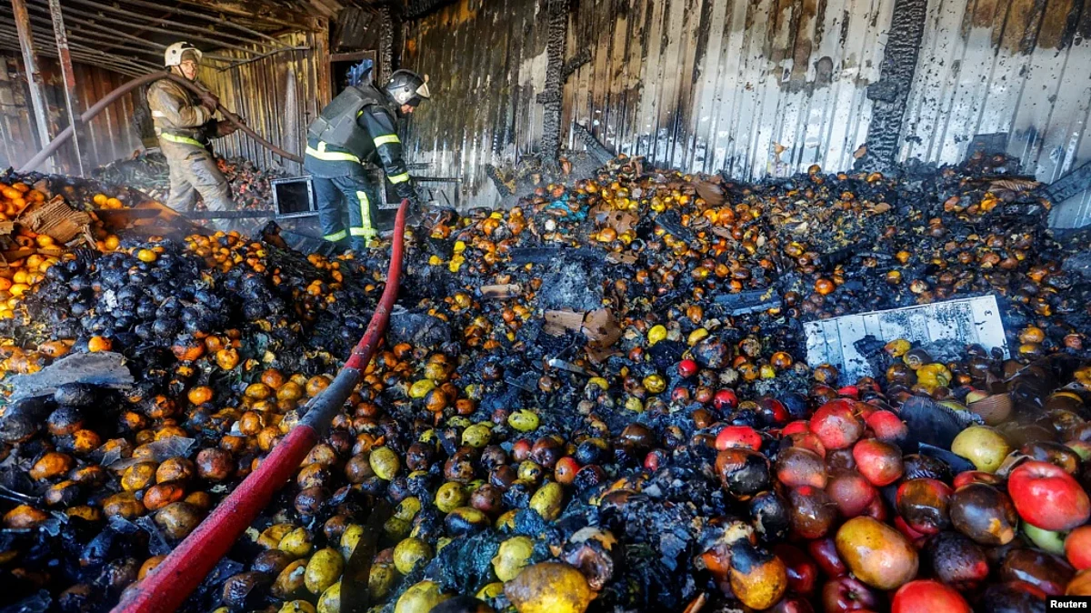 Firefighters stand on heaps of fruit while working inside burnt market stalls hit by shelling in the course of Russia-Ukraine conflict in Donetsk, Russian-controlled Ukraine, Dec. 6, 2022. (VOA)