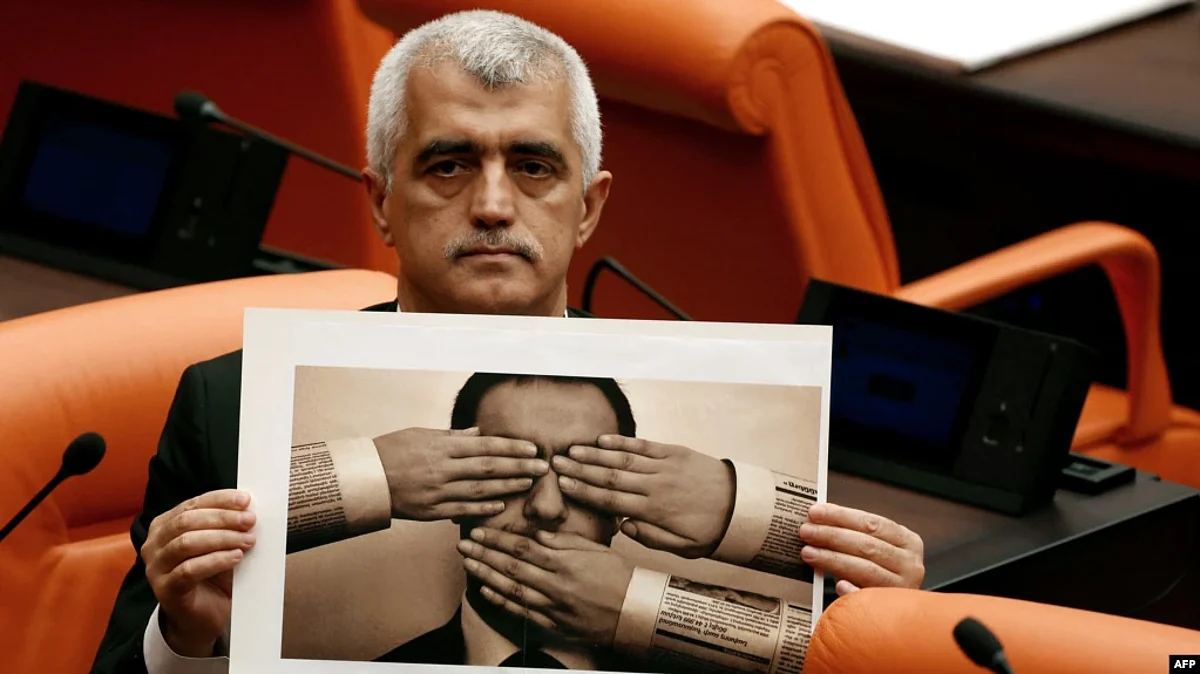 Peoples' Democratic Party MP Omer Faruk Gergerlioglu holds a photograph depicting censorship while attending a session on a government-sponsored bill that criminalizes "disinformation" at the Turkish Grand National Assembly on Oct.13, 2022, in Ankara. (AFP)