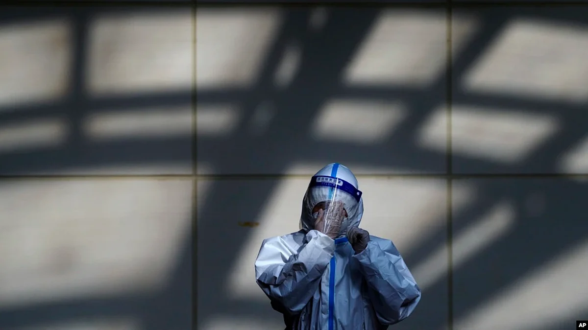 A worker in protective suit wipes his face shield at a coronavirus testing side in Beijing, Monday, Dec. 5, 2022. (VOA)