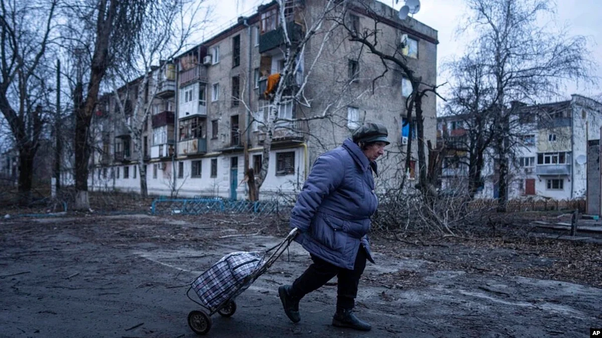 A local woman walks to the distribution point of humanitarian aid in front of housing which was damaged by Russian shelling in Kupiansk, Kharkiv region, Ukraine, Dec. 28, 2022. (AP)