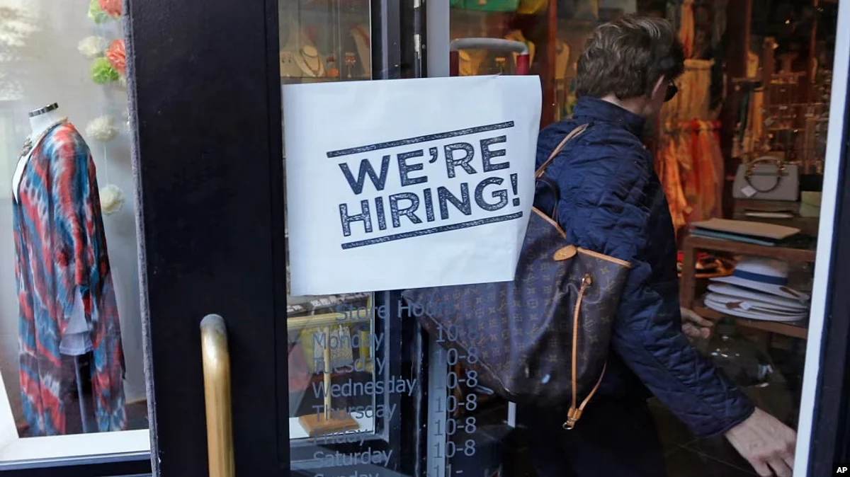 FILE - In this May 18, 2016, file photo, a woman passes a "We're Hiring!" sign while entering a clothing store in the Downtown Crossing of Boston. (AP)