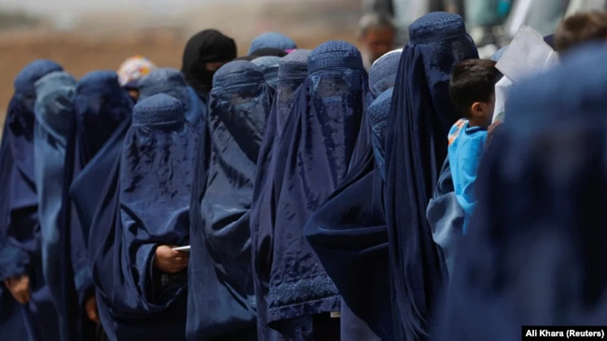 Displaced Afghan women wait in line to receive cash aid in Kabul. (Reuters)