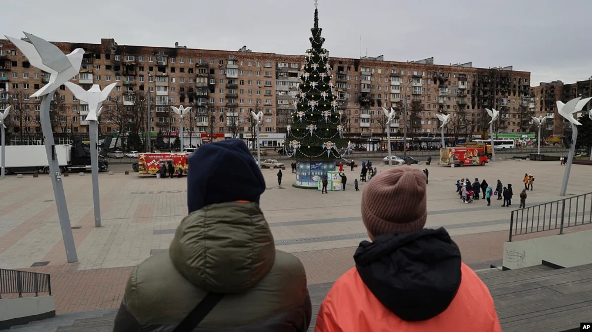 Local citizens walk near a Christmas tree decorated for Orthodox Christmas and the New Year festivities in Mariupol, in Russian-controlled Donetsk region, eastern Ukraine, Jan. 5, 2023. (AP)