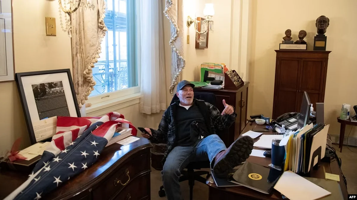 FILE - Richard Barnett, a supporter of President Donald Trump sits inside the office of then-U.S. Speaker of the House Nancy Pelosi during the U.S. Capitol Hill riot, in Washington, Jan. 6, 2021.
