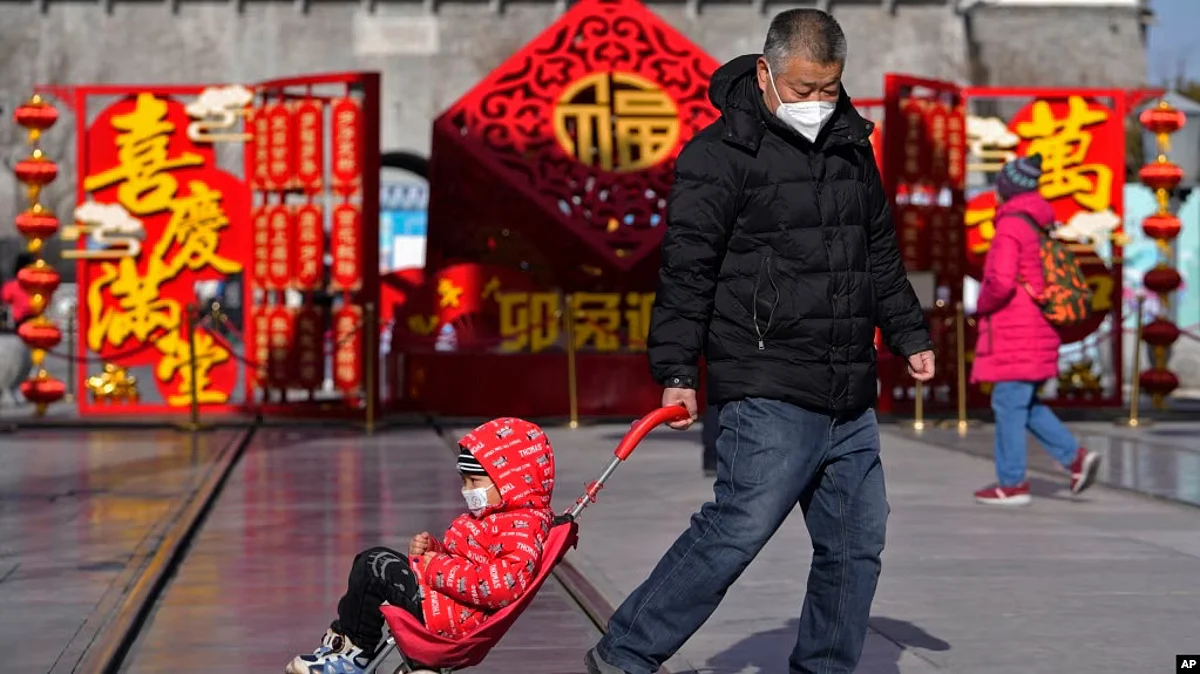 A man pulls a child past a Lunar New Year decoration on display at the Qianmen pedestrian shopping street, a popular tourist spot in Beijing, Jan. 17, 2023. (AP)