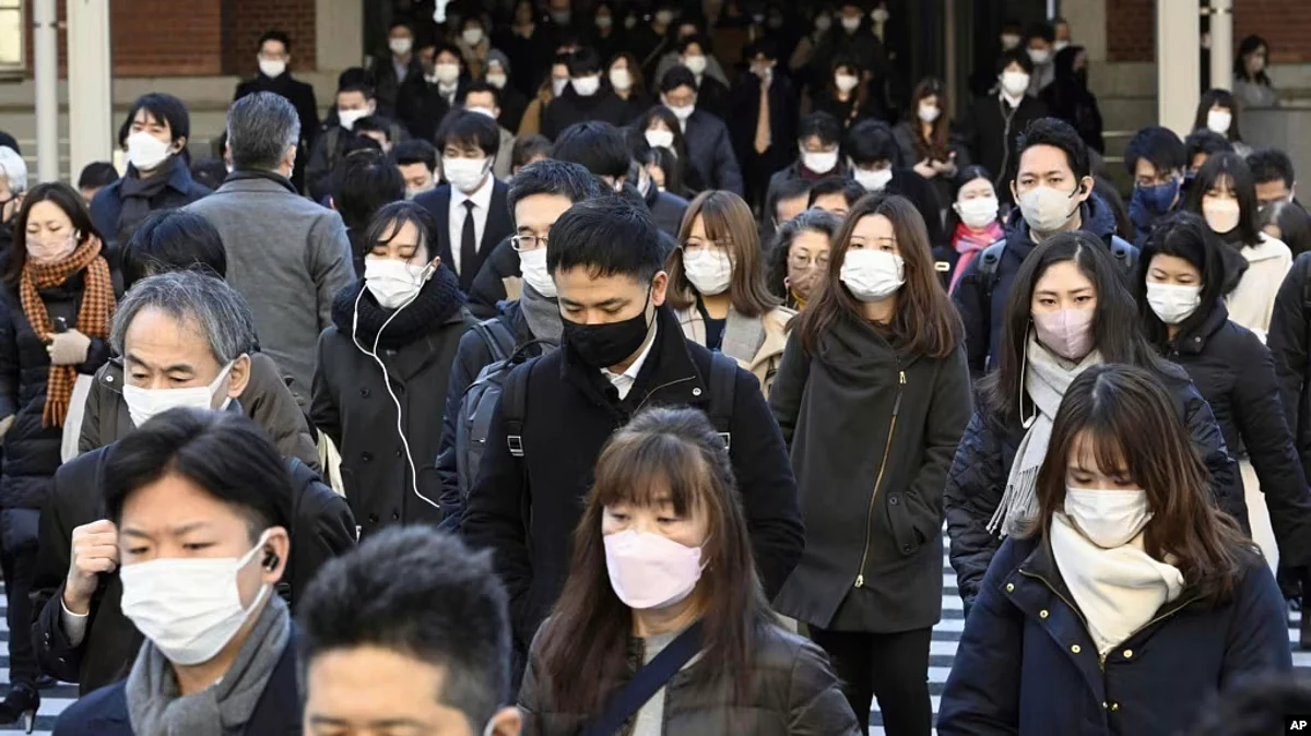 People wear face masks as they leave a train station in Tokyo, Jan. 20, 2023. (AP)