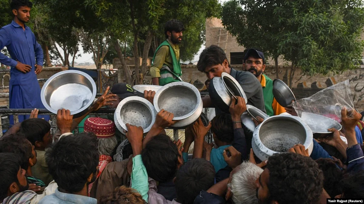 People who were displaced during severe flooding receive food handouts at an aid camp in Sehwan, Pakistan, on September 11, 2022. (Reuters)
