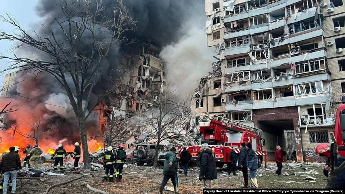 Rescuers and residents stand by the site of an apartment building heavily damaged by a Russian missile strike in Dnipro on January 14. (Reuters)
