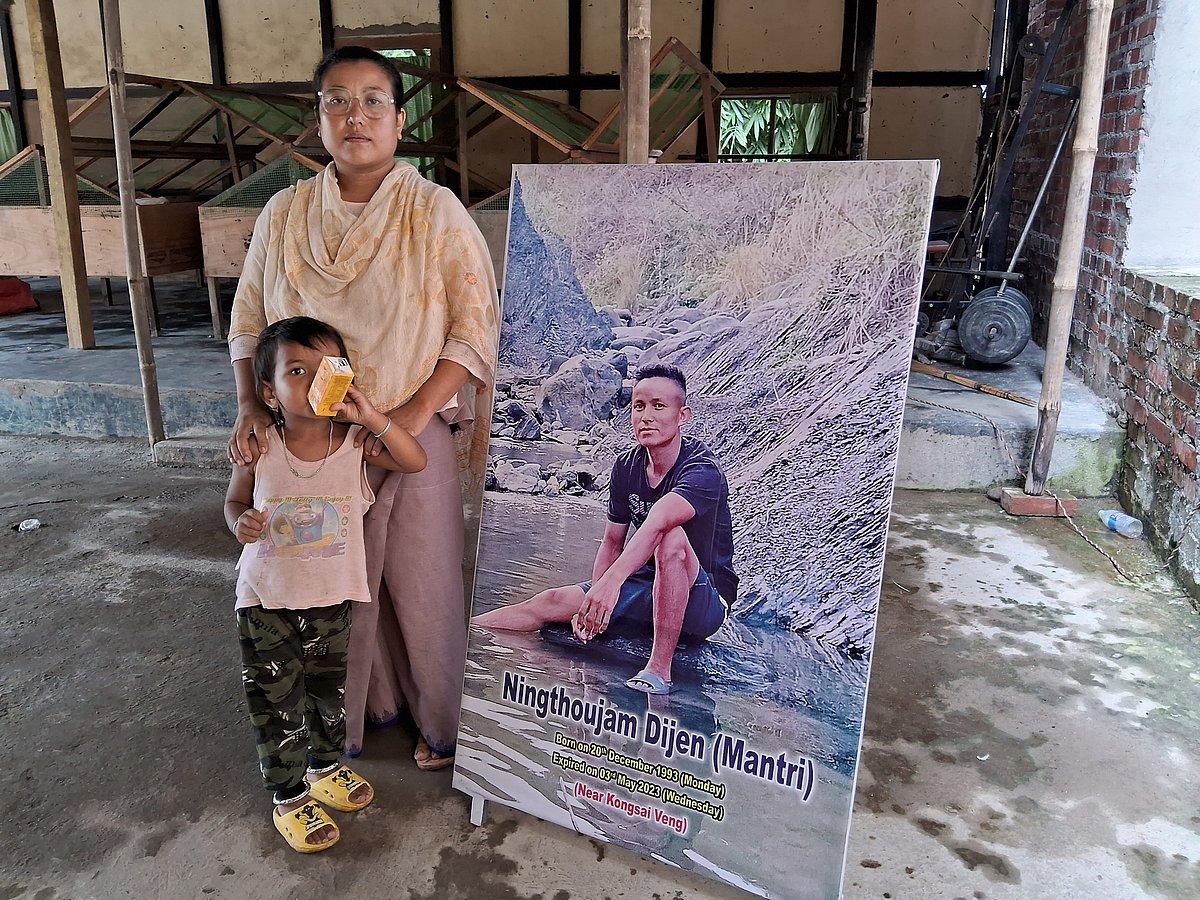 Shanti Bala with her daughter, next to a picture of her deceased husband Ningthoujam Dijen Singh.