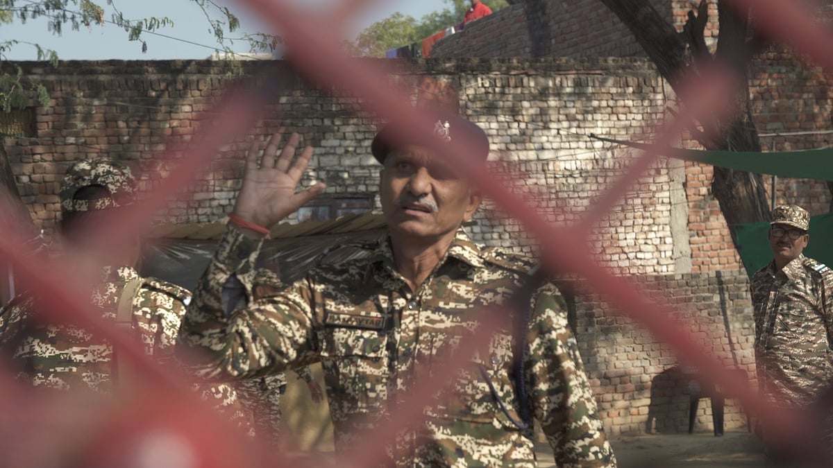 CRPF personnel try to stop the media near the victim's residence.