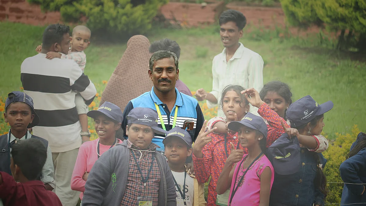 A group of children pose with camp coordinator Thangeswaran during an outing at the Theni summer camp.