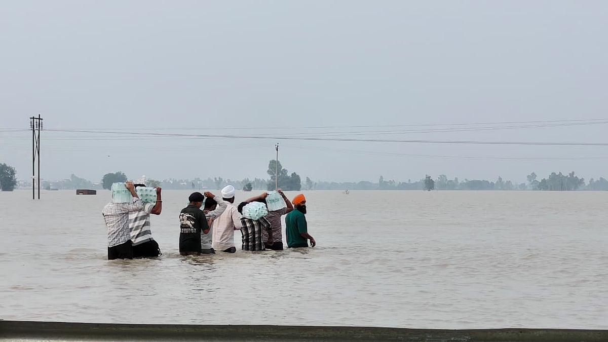 बाढ़ के पानी के बीच मदद पहुंचाने जाते लोग