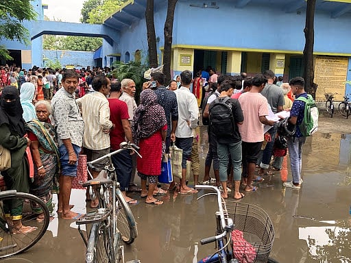 People standing in queues in a waterlogged area waiting for their turn. (Image courtesy Suhasini Biswas)