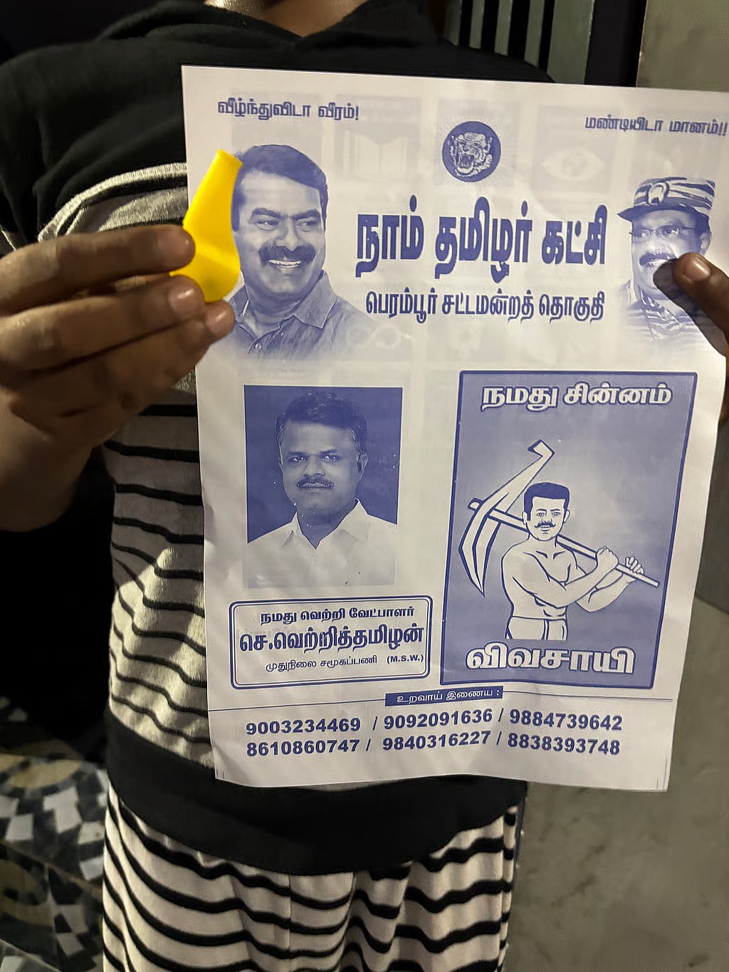 A young supporter holds a Naam Tamilar Katchi (NTK) pamphlet featuring Seeman.