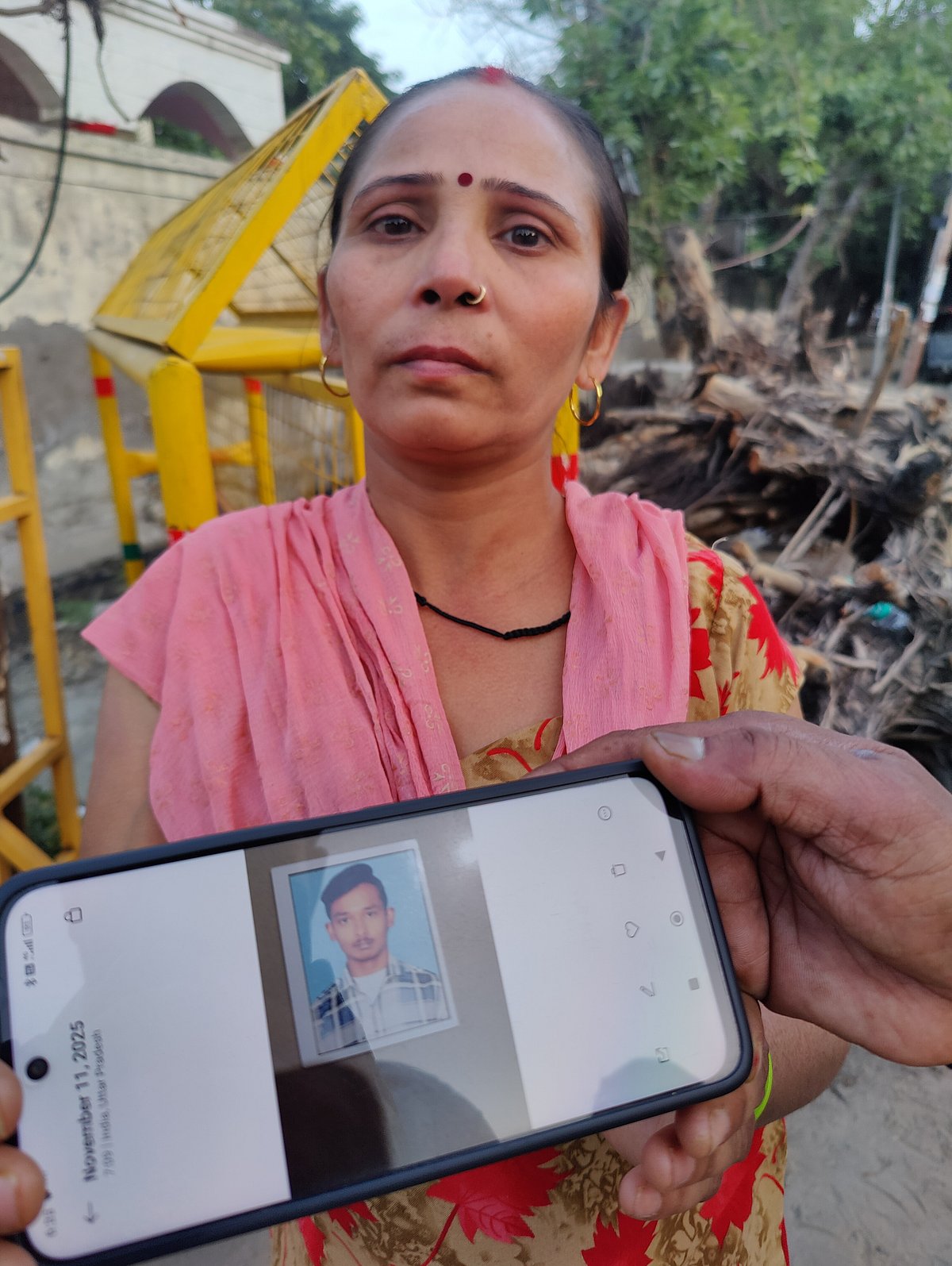 Bhawana is standing behind a photo of her son, Indrajeet. 