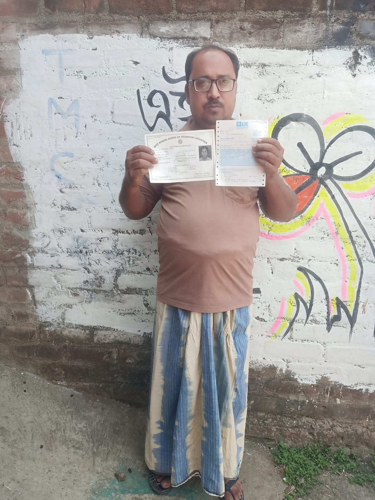 Md Anikul Hoque holding up documents outside his home in Murshidabad's Samserganj.