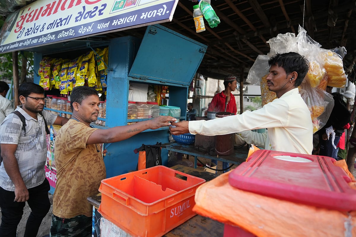 Sibaram Pradhan takes a tea from a stall near the factory where he works. (AP Photo/Ajit Solanki)