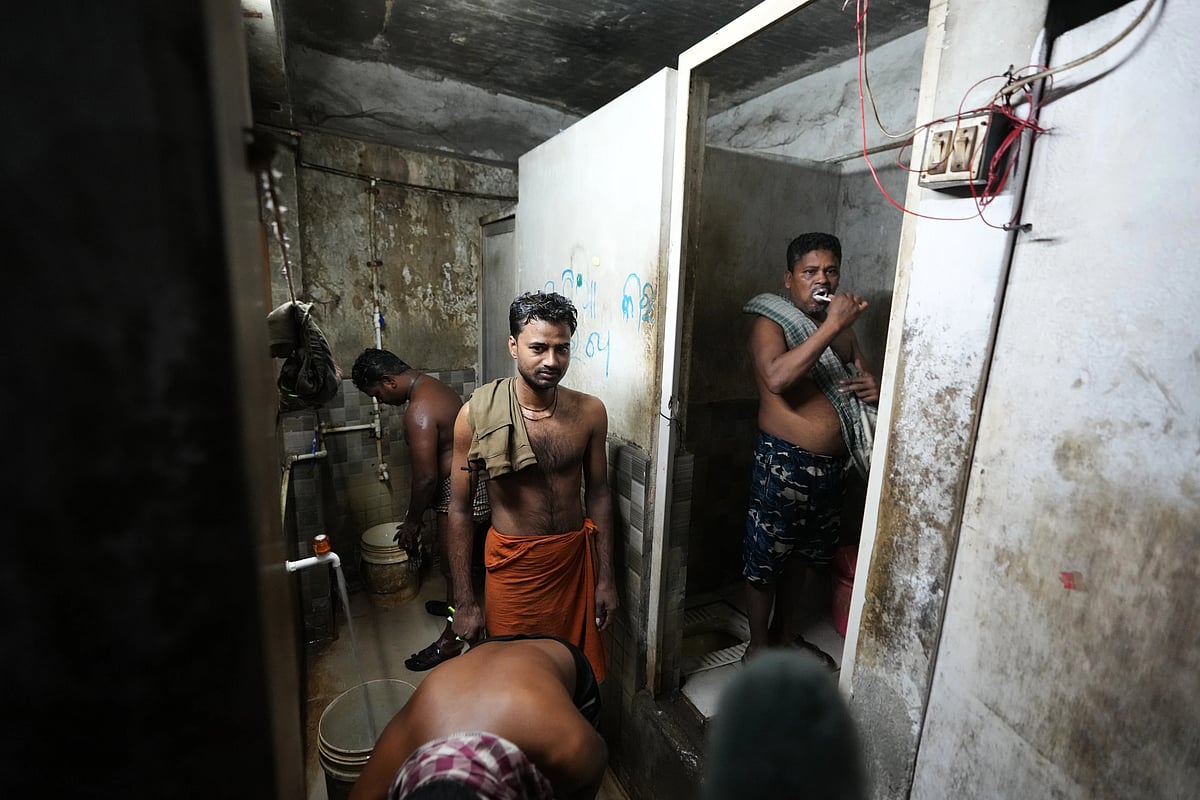 Power loom factory worker Sibaram Pradhan, right, brushes his teeth as others bathe at their residential quarters. (AP Photo/Ajit Solanki)