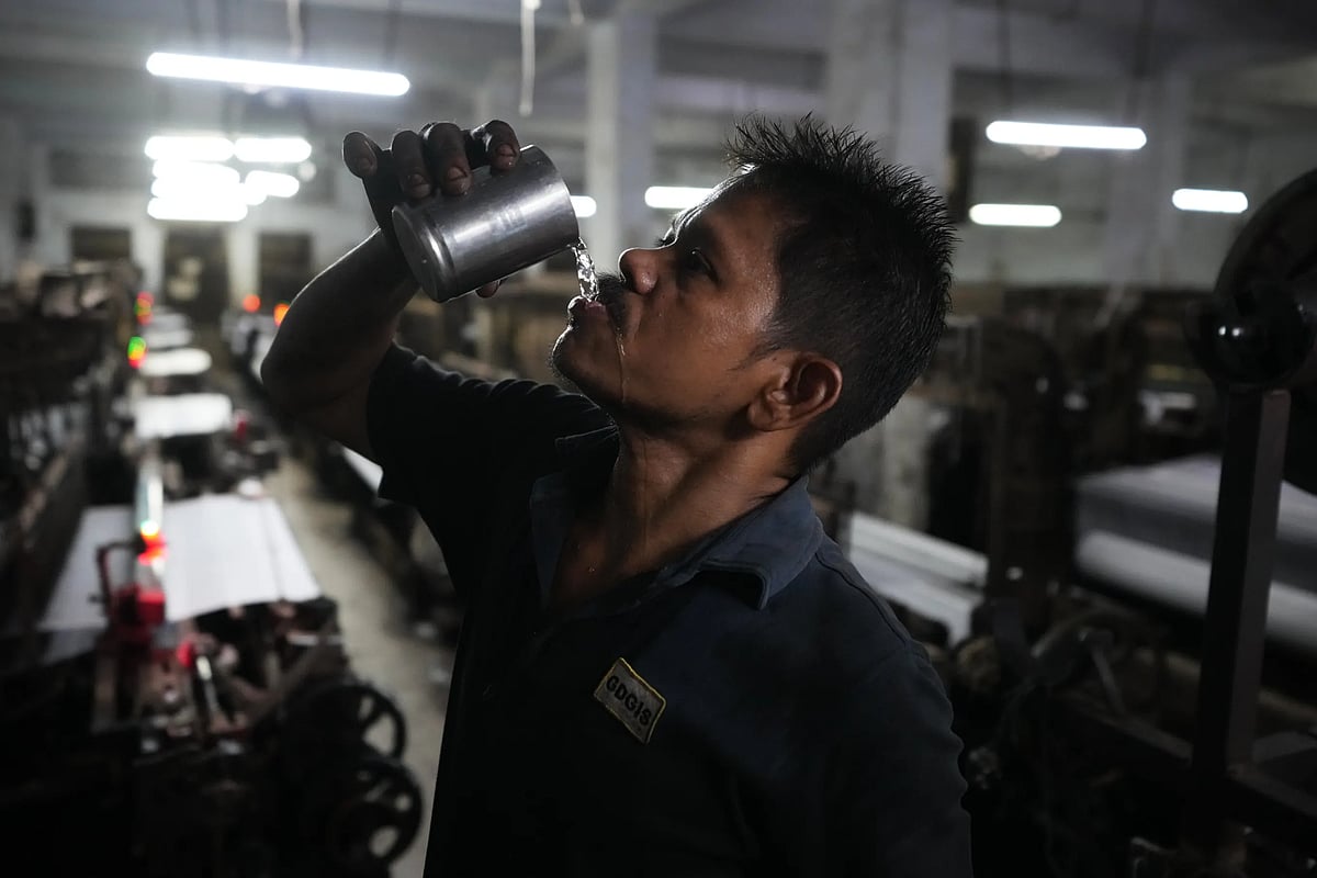 Seemanchal Sahu drinks water as he works at a power loom factory in Surat. (AP Photo/Ajit Solanki)