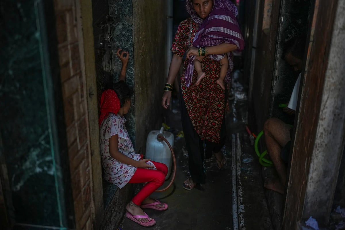 A girl fills water in a narrow lane of a slum settlement in Mumbai. (AP Photo/Rafiq Maqbool)