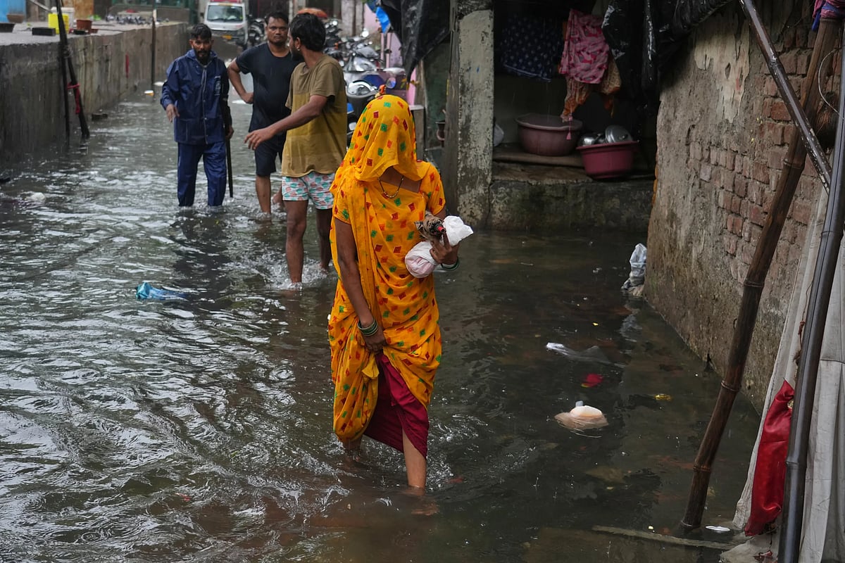 A woman walks through a waterlogged slum following monsoon rains in Mumbai. (AP Photo/Rafiq Maqbool)