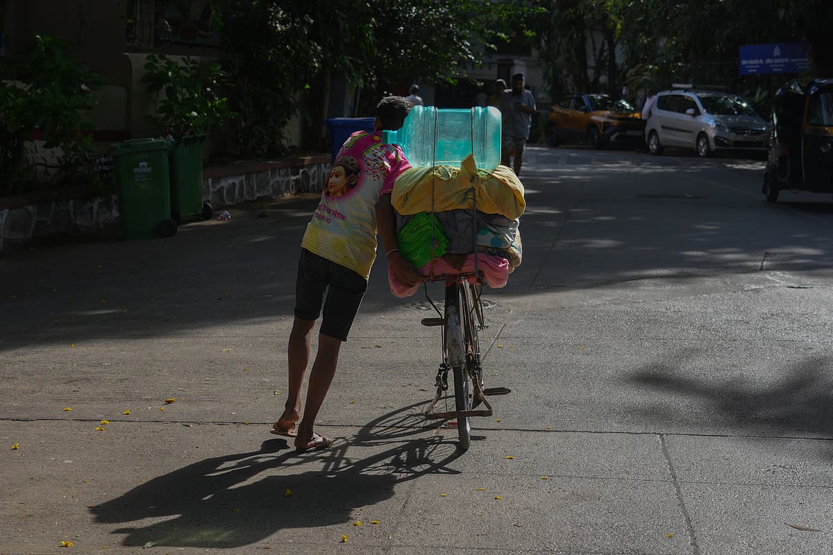 A washerman carries a water can on his bicycle on a hot day in Mumbai. (AP Photo/Rafiq Maqbool)