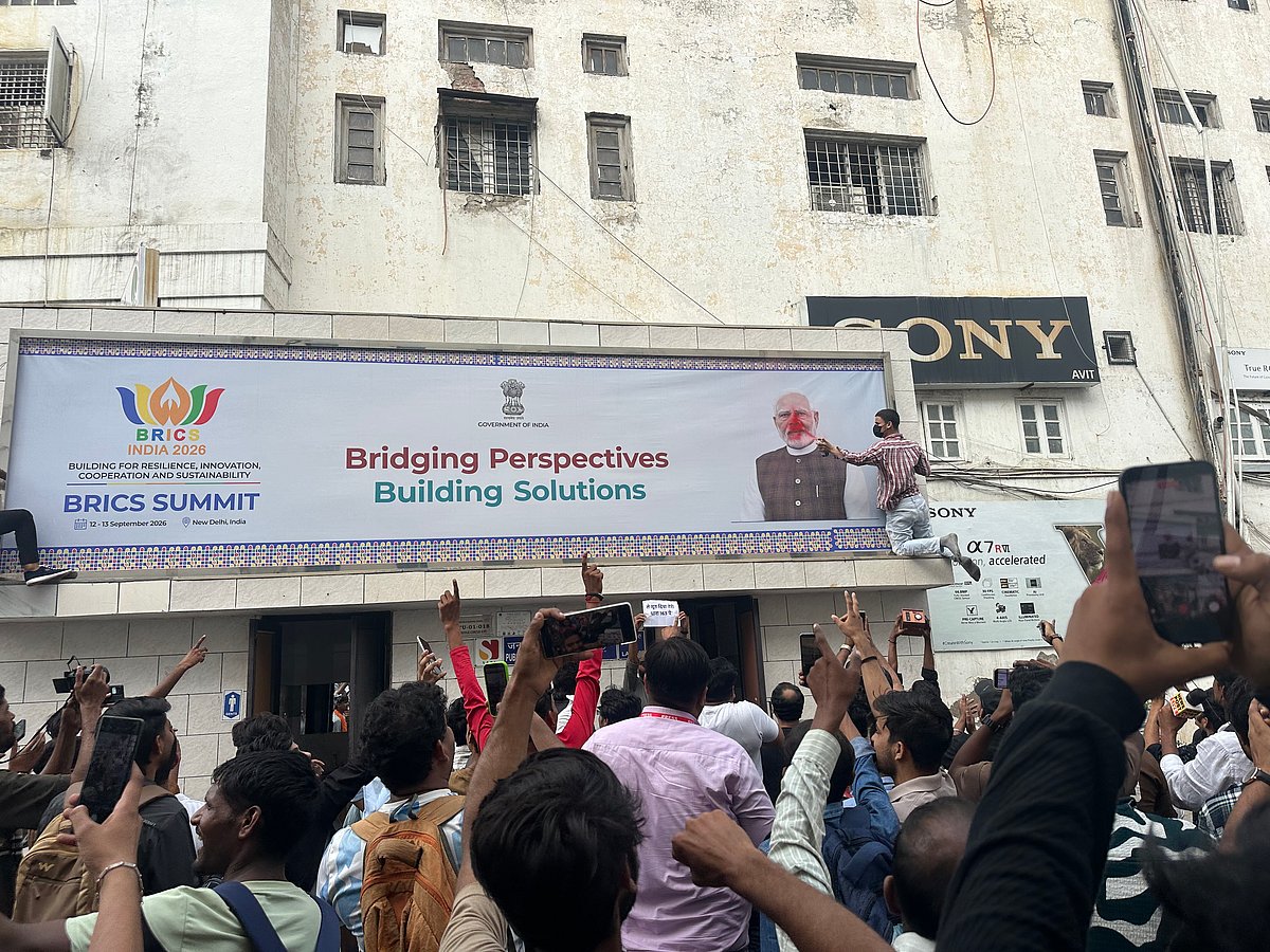 On Middle Circle Road in Connaught Place, protestors climb and tear off a hoarding