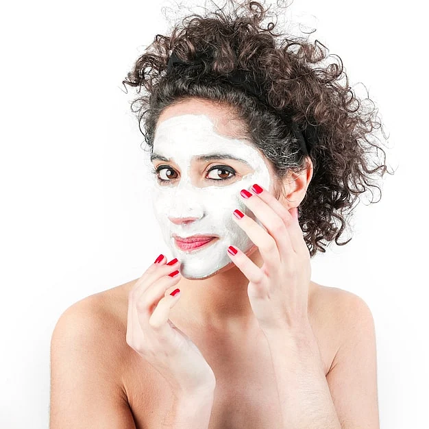 woman with curly hair applying facial cream her face against white background23 2147901166