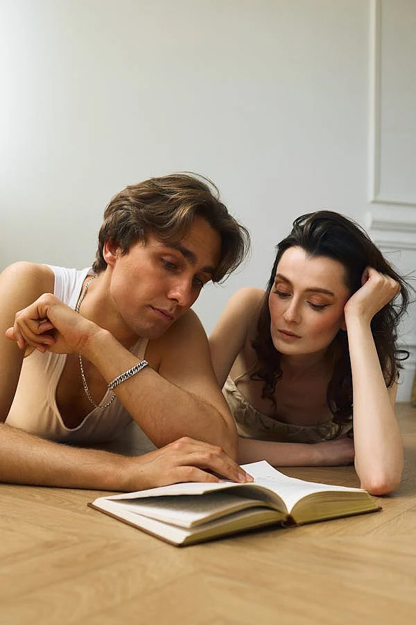 free photo of couple lying down on floor and reading book