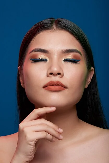 asian woman with full makeup bare shoulders posing with closed eyes finger chin 1098 17119