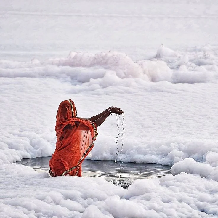 A woman offers prayers after a dip in the polluted…