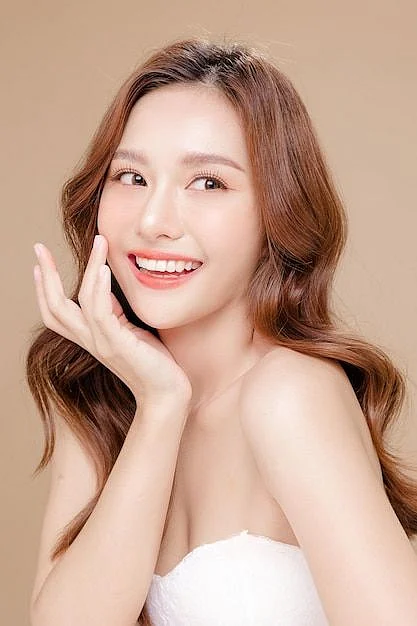 Premium Photo Young Asian beauty woman curly long hair with korean makeup style touch her face and perfect skin on isolated beige background Facial treatment Cosmetology plastic surgery