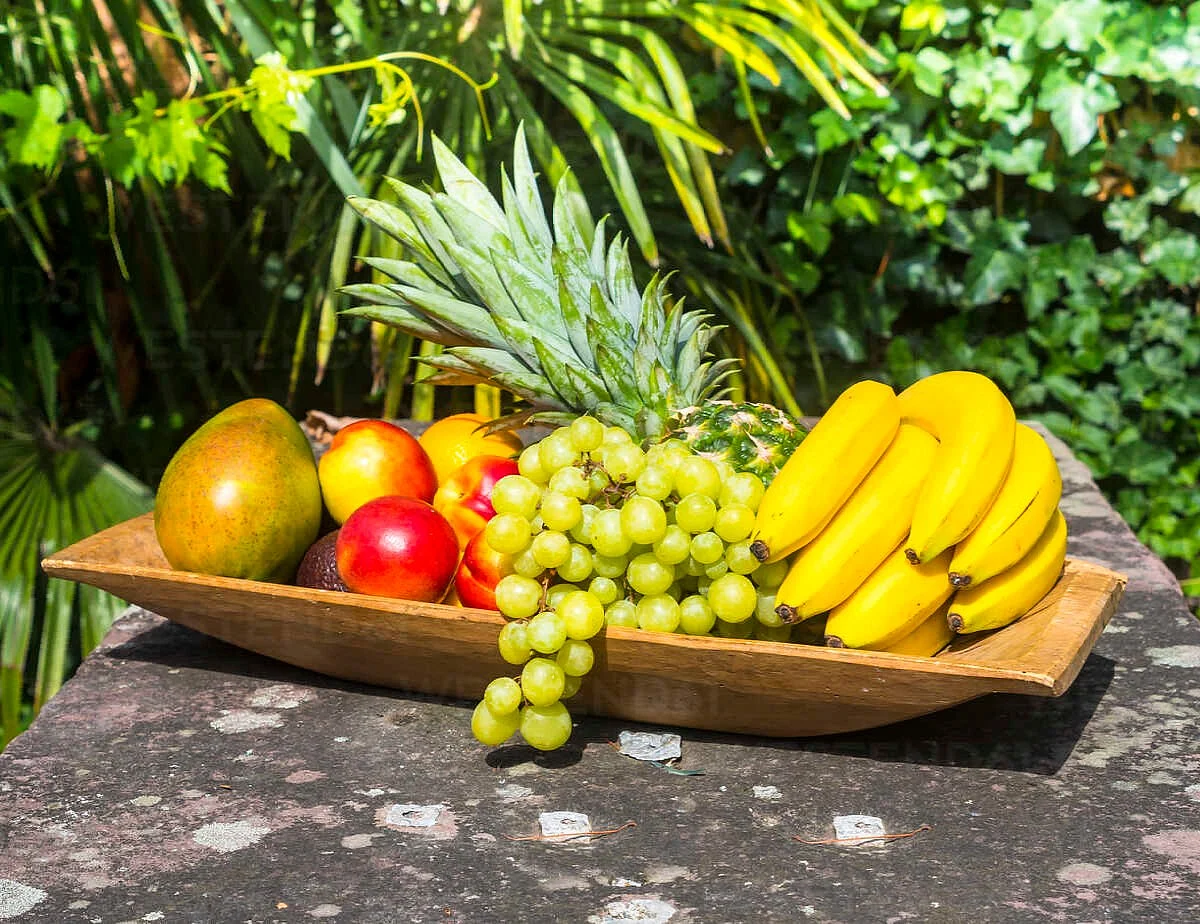 wooden plate of bananas pineapple green grapes mango and nectarines AMF004133