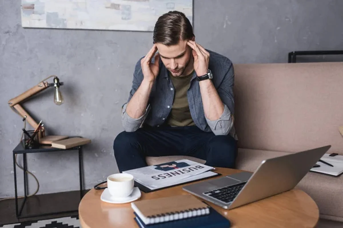 depositphotos 184221646 stock photo young businessman headache sitting couch 1