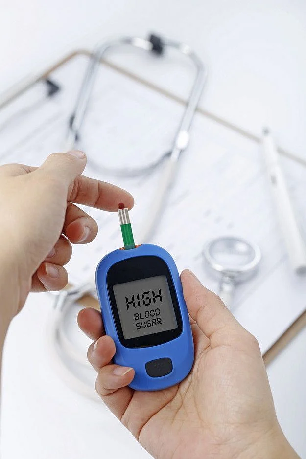 Free Photo Hand holding a blood glucose meter measuring blood sugar the background is a stethoscope and chart file