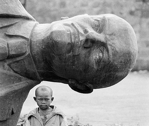 A boy stands beside a toppled Lenin statue in Ethiopia in 1991. (image via Reddit) 