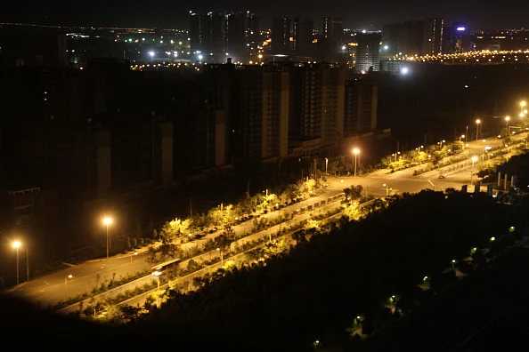 A bus is driven along an illuminated street in Chenggong, Yunnan Province of China. As of 2012, much of the newly constructed housing in Chenggong was still unoccupied, and it is reportedly one of the largest ghost towns in Asia.