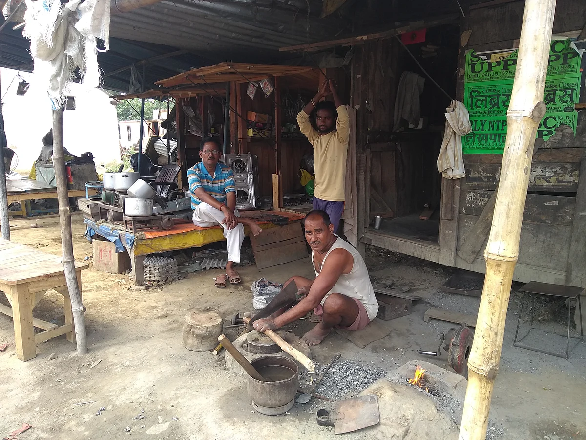 Inderdev Vishwakarma working outside his iron workshop. Veeru Kumar (right) and Jitender Singh in the background. (Prakhar Gupta/Swarajya Magazine)