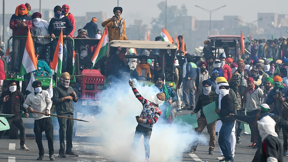 A farmer throws back a tear gas shell fired by the police to disperse them during the tractor rally on January 26
